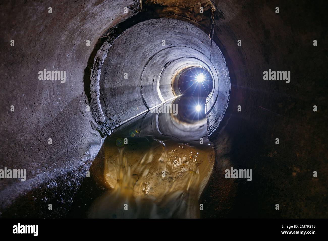 Sewage flowing inside round underground urban sewer tunnel Stock Photo