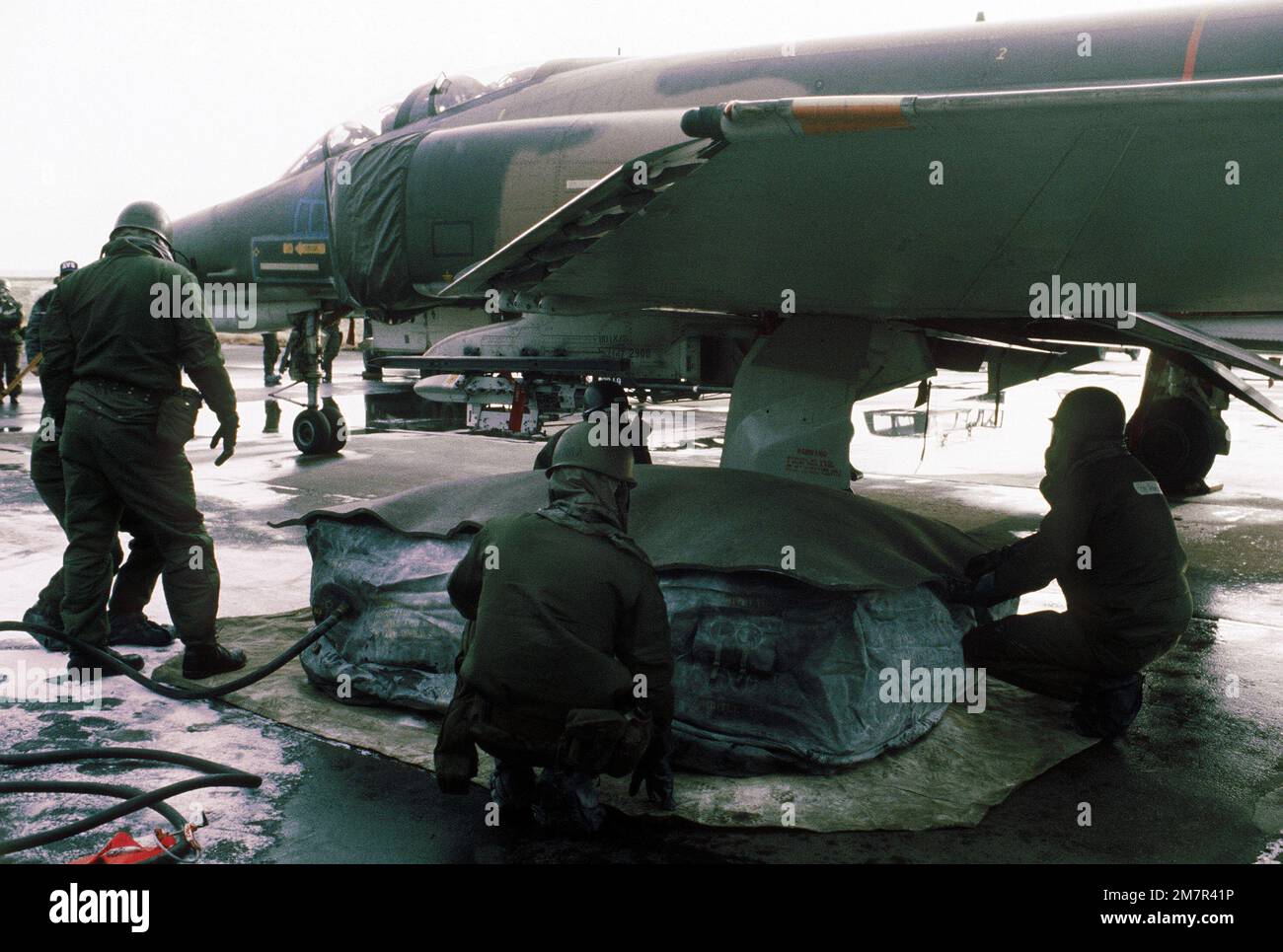 Members of the 50th Civil Engineering Squadron repair a simulated flat tire of an F-4E Phantom II aircraft during the chemical warfare exercise Salty Mace. Subject Operation/Series: SALTY MACE Base: Hahn Air Base Country: Federal Republic Of Germany (FRG) Stock Photo