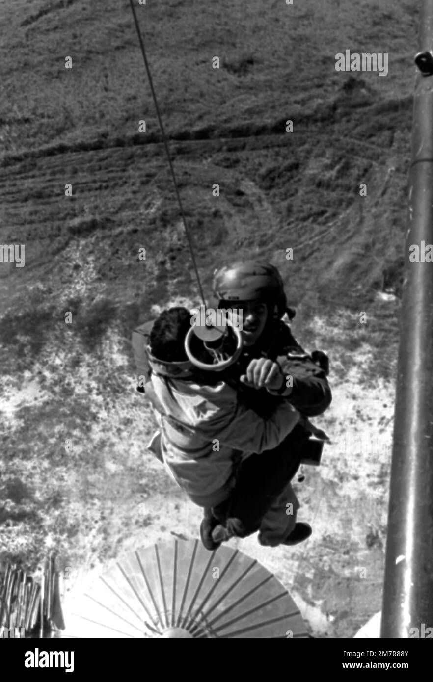 Pararescueman A1C Lawrence Davis, on a jungle penetrator holding an injured man, is being hoisted up from atop a grain elevator into a hovering helicopter. Davis is from the 40th Aerospace Rescue and Recovery Service, Air Force Rescue Coordination Center. State: Washington (WA) Country: United States Of America (USA) Stock Photo