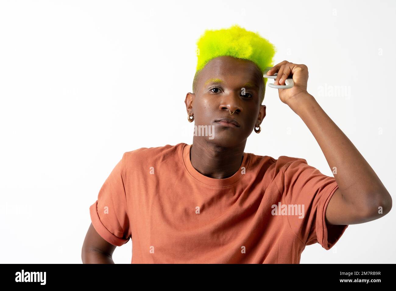 Gay black ethnic man putting on makeup, LGTBI concept, combing his gorgeous green hair Stock Photo