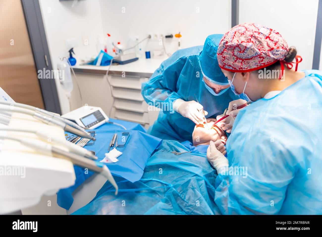 Dental clinic, dentists in blue suits performing an operation on an implant Stock Photo