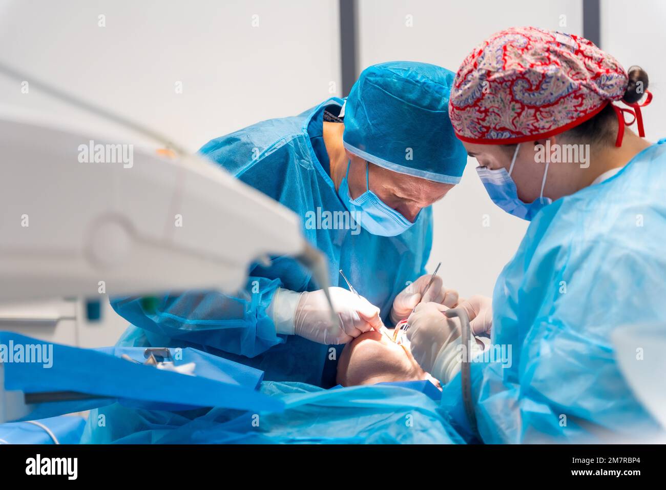Dental clinic, women dentists in blue suits and hats performing an oral