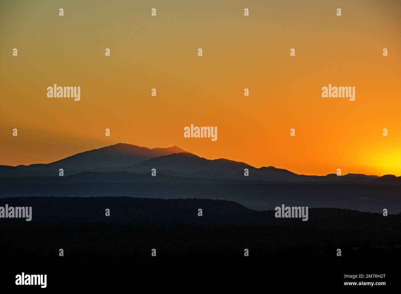 sunrise golden sky over the San Francisco Peaks and Mount Humphreys in Northern Arizona Stock Photo