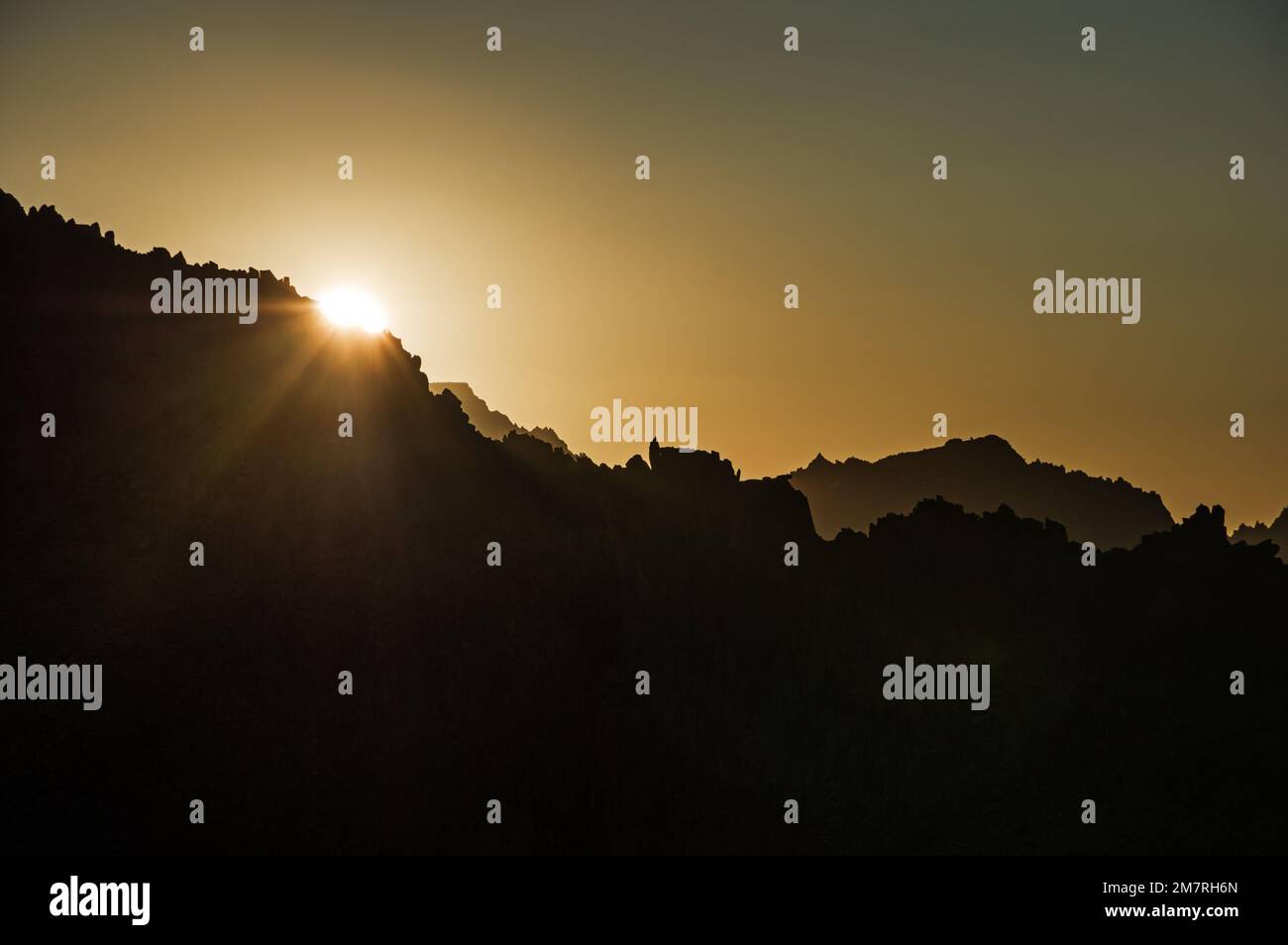 sun setting over a mountain ridge in the Sierra Nevada Mountains Stock Photo