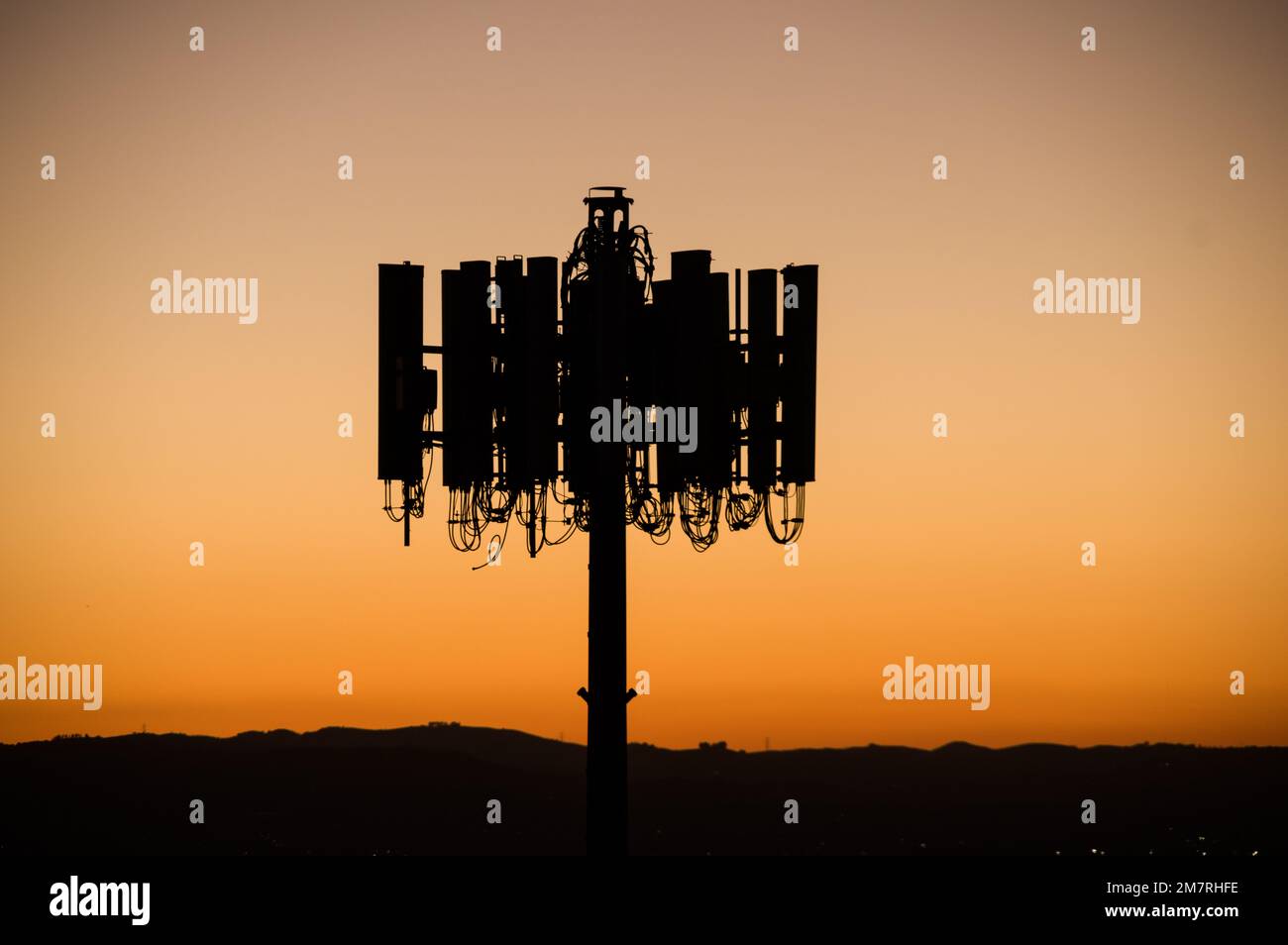 silhouette of cell phone tower antennas against an evening sky Stock Photo