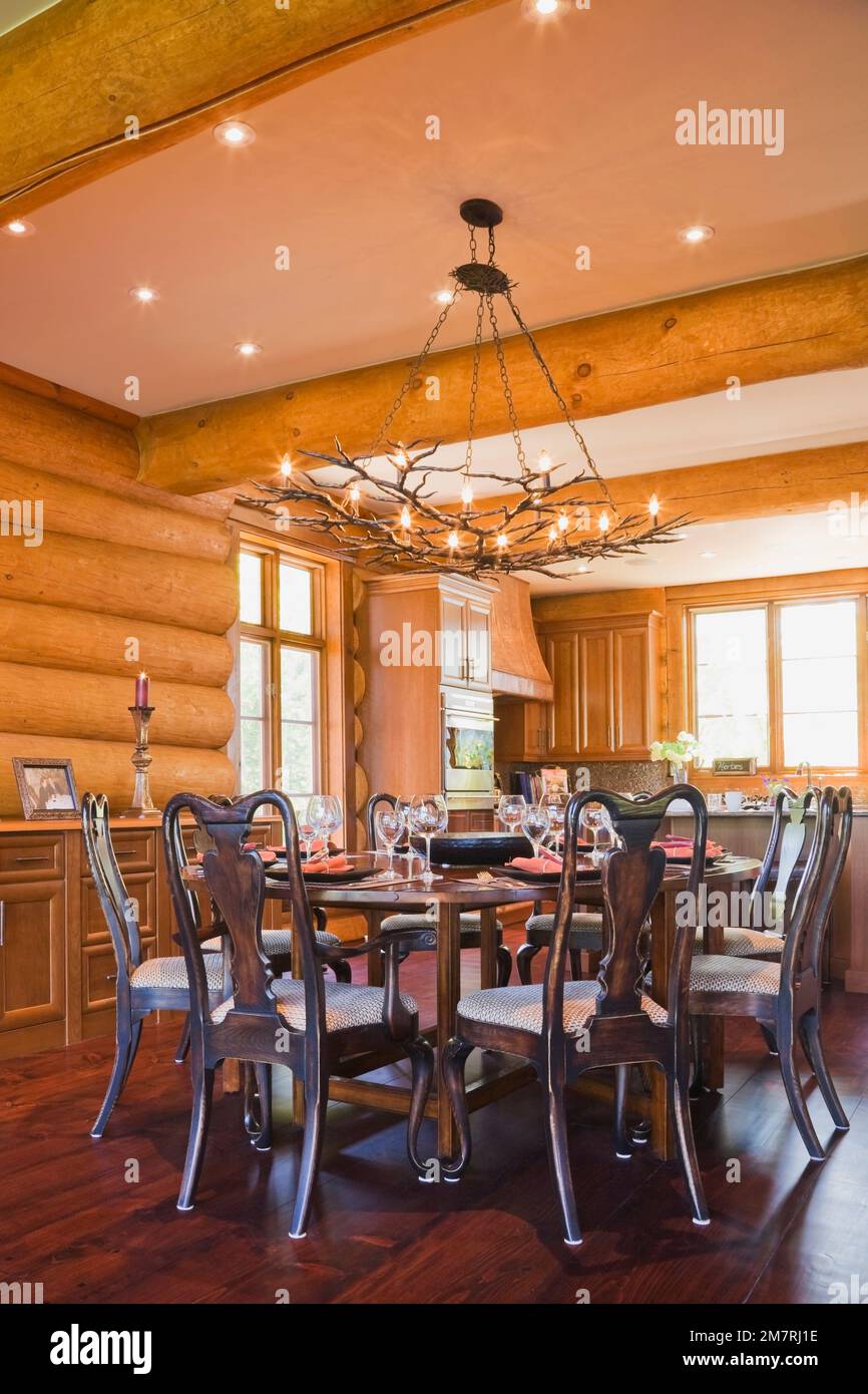 Round wooden dining room table with high back chairs and kitchen inside