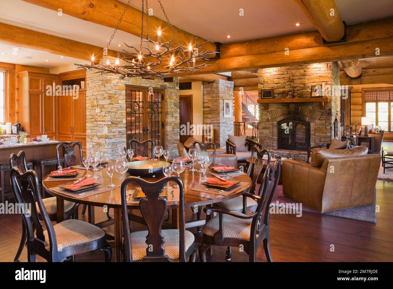 Round wooden dining room table with high back chairs and kitchen island