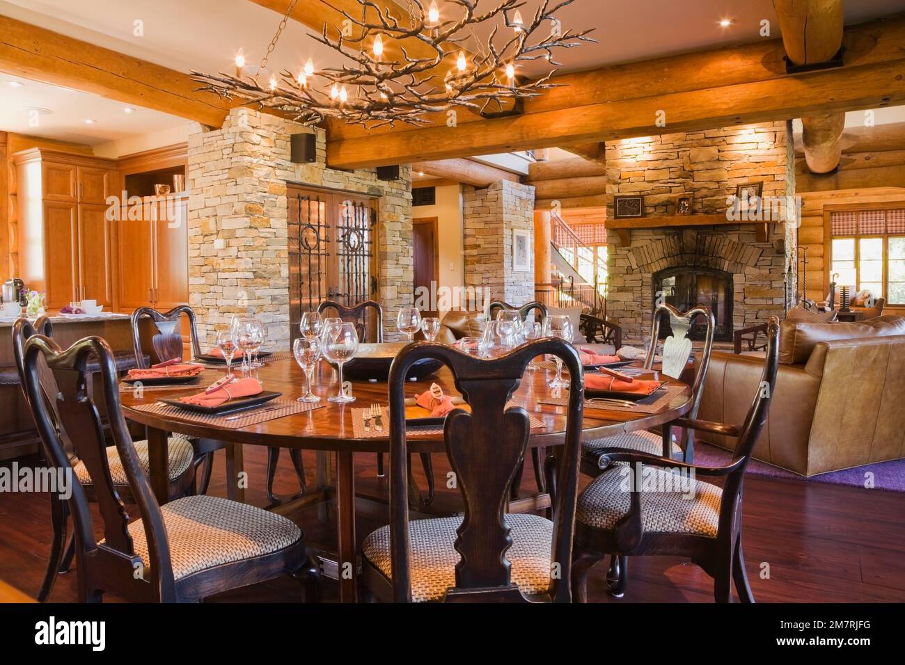 Round wooden dining room table with high back chairs and kitchen island