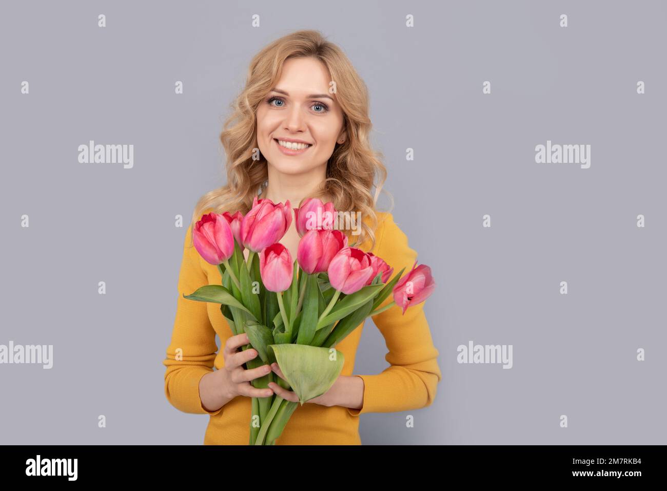 happy girl hold flowers for spring holiday on grey background Stock Photo
