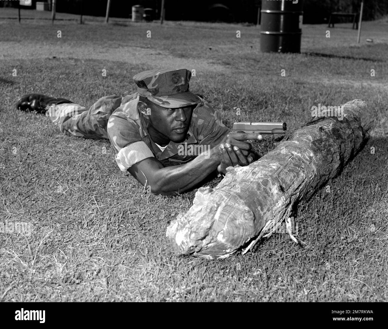 SGT. M. W. Patrick, a military policeman, is in the prone position and uses a dead tree log for protection from possible hostile fire. He is using the Colt .45-caliber pistol at the police protective course, which is a part of a 200-hour training program for the base military police. Base: Albany State: Georgia (GA) Country: United States Of America (USA) Stock Photo