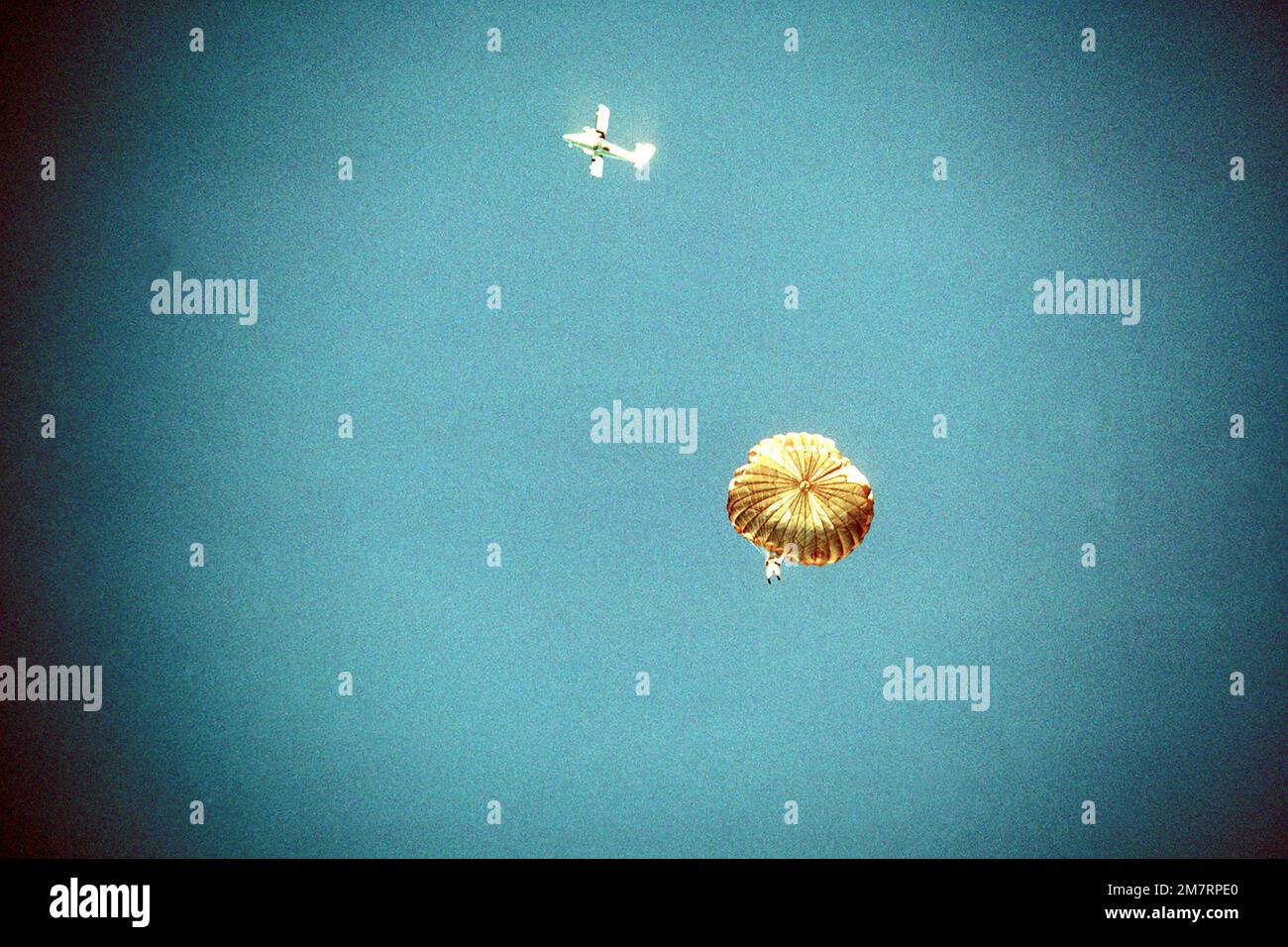 A cadet parachutes after jumping from a Twin Otter aircraft (background