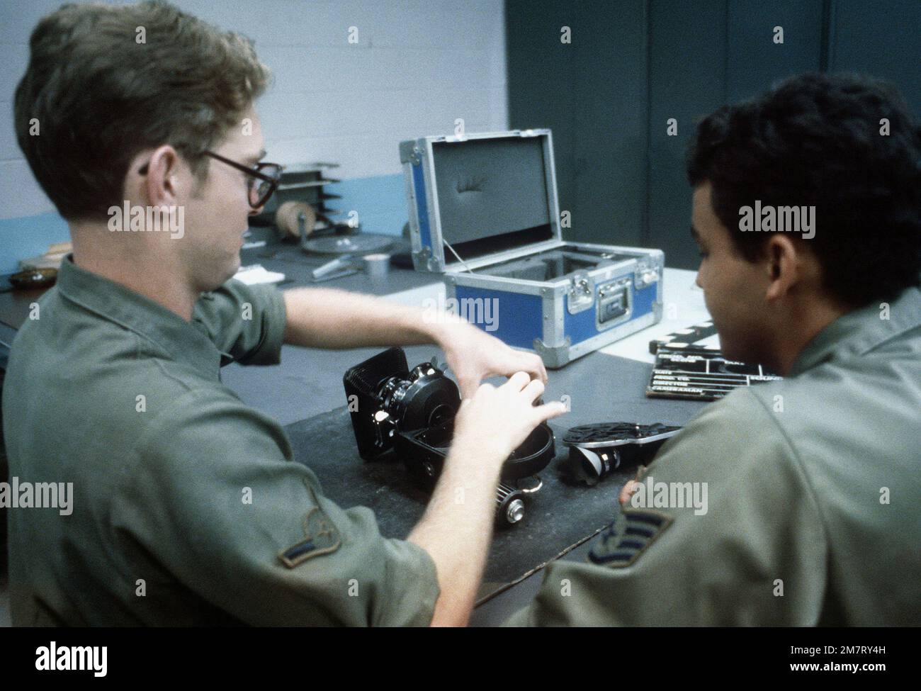 AMN Brant R. McCarthy receives training from SSGT John W. Rodrigues on the 16mm movie camera, during a mission briefing for the 1361st Audio Visual Squadron, Detachment Seven. Base: Charleston Air Force Base State: South Carolina (SC) Country: United States Of America (USA) Stock Photo