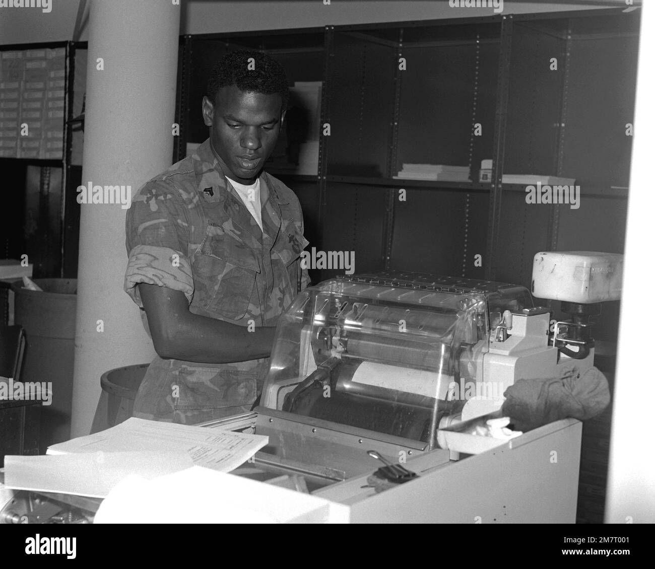 CPL Victor Branch checks the alignment of the Multilith 1250 offset press as the copy material comes off the machine. This piece of equipment is in the Reproduction Section of the Graphic Arts Branch of the Facilities and Services Division at the Marine Corps Logistics Base. Base: Albany State: Georgia (GA) Country: United States Of America (USA) Stock Photo