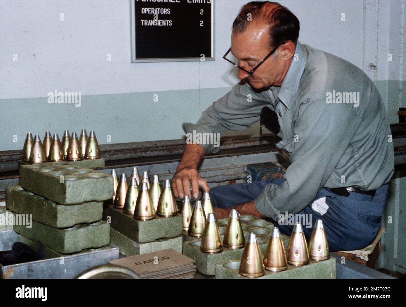 A civilian worker gages standard contour 557 artillery fuses at the