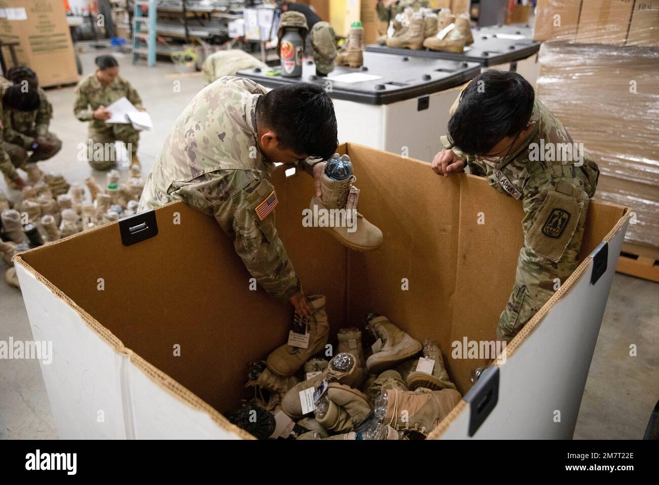 Cpl. Ernesto Atilano and Spc. Farhanur Rahman, Headquarters and Headquarters Company, 11th Signal Brigade, reach for combat boots from their storage container while volunteering May 12, 2022, at Fort Hood, Texas, in preparation for the Memorial Remembrance Boot Display. This year marks the eighth annual display honoring those who gave the ultimate sacrifice. Each fallen Fort Hood service member is represented with a combat boot featuring the service member's name and photo, alongside an American flag. Stock Photo
