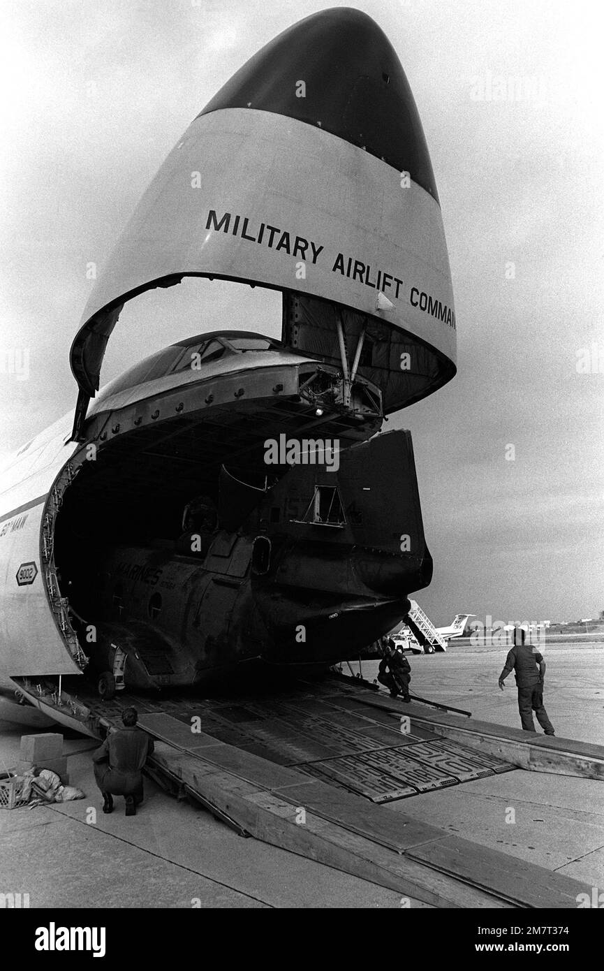 Marines and Air Force personnel load a CH-46 Sea Knight helicopter into a C-5A Galaxy aircraft at MCAS (H) Futenma. Three CH-46's are being loaded aboard the C-5A for transport to MCAS (H) Tustin, California, via Hawaii. The helicopters are from Marine Medium Helicopter Squadron 163 (HMM-163). State: Okinawa Country: Japan (JPN) Stock Photo