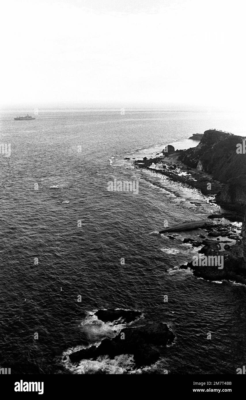 An aerial view of the overturned Filipino frigate RPS DATU KALANTIAW (PS-76) lying among the rocks as the ammunition ship USS MOUNT HOOD (AE-29) stands by offshore to assist in rescue operations. The frigate was overtaken by Typhoon Clara. Base: Calayan Island Country: Philippines Stock Photo