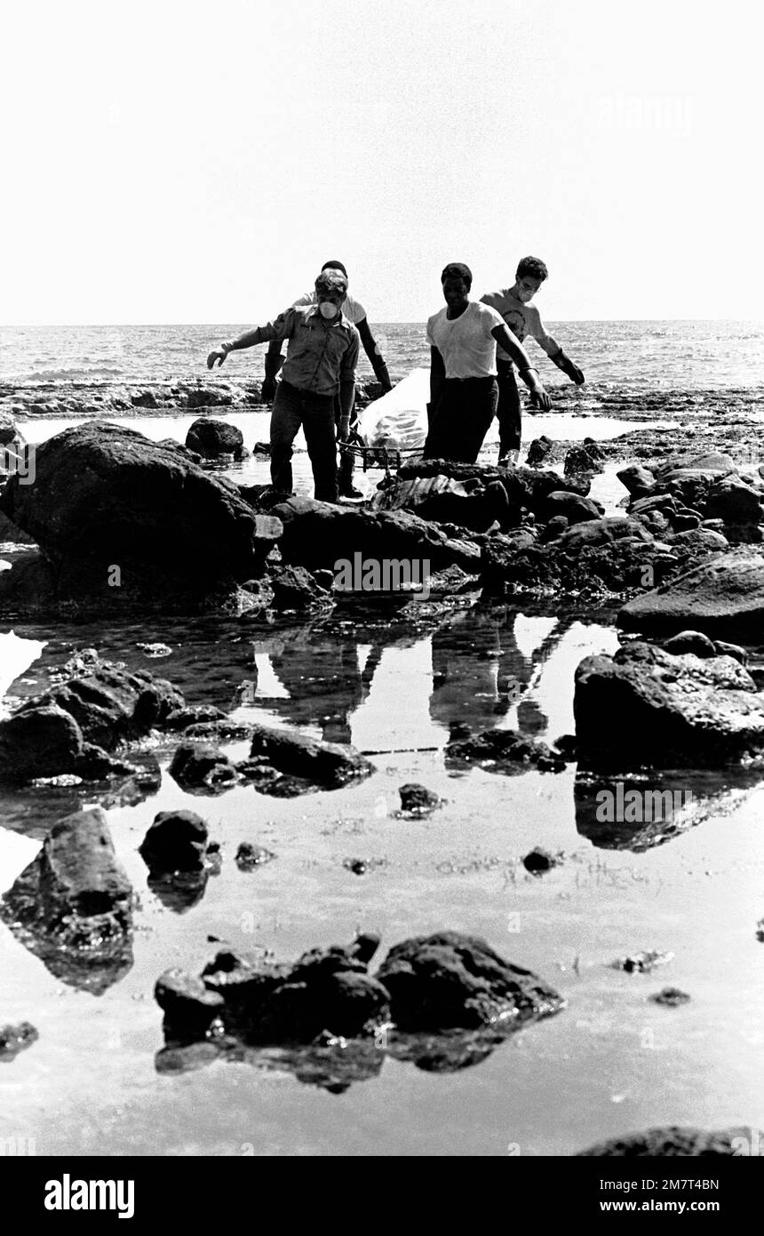 Four crewmen from the ammunition ship USS MOUNT HOOD (AE-29) carry a body over rocks during search and rescue (SAR) operations for the beached and overturned Filipino frigate RPS DATU KALANTIAW (PS-76). The frigate was overtaken by Typhoon Clara. Base: Calayan Island Country: Philippines Stock Photo