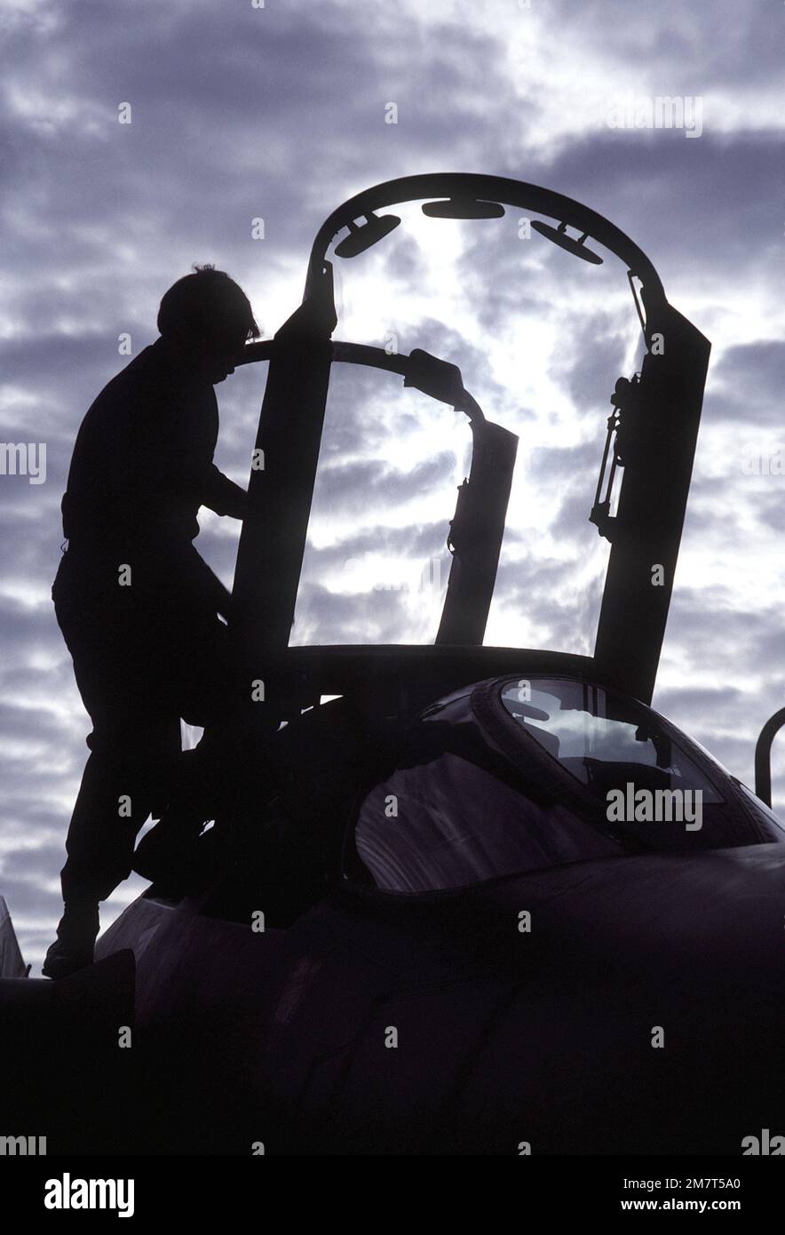 A flight crewman is silhouetted against the cloudy sky as he prepares an F-4E Phantom II aircraft for flight during exercise PHOTO Finish '81. Subject Operation/Series: PHOTO FINISH '81 Base: Gulfport State: Mississippi (MS) Country: United States Of America (USA) Stock Photo