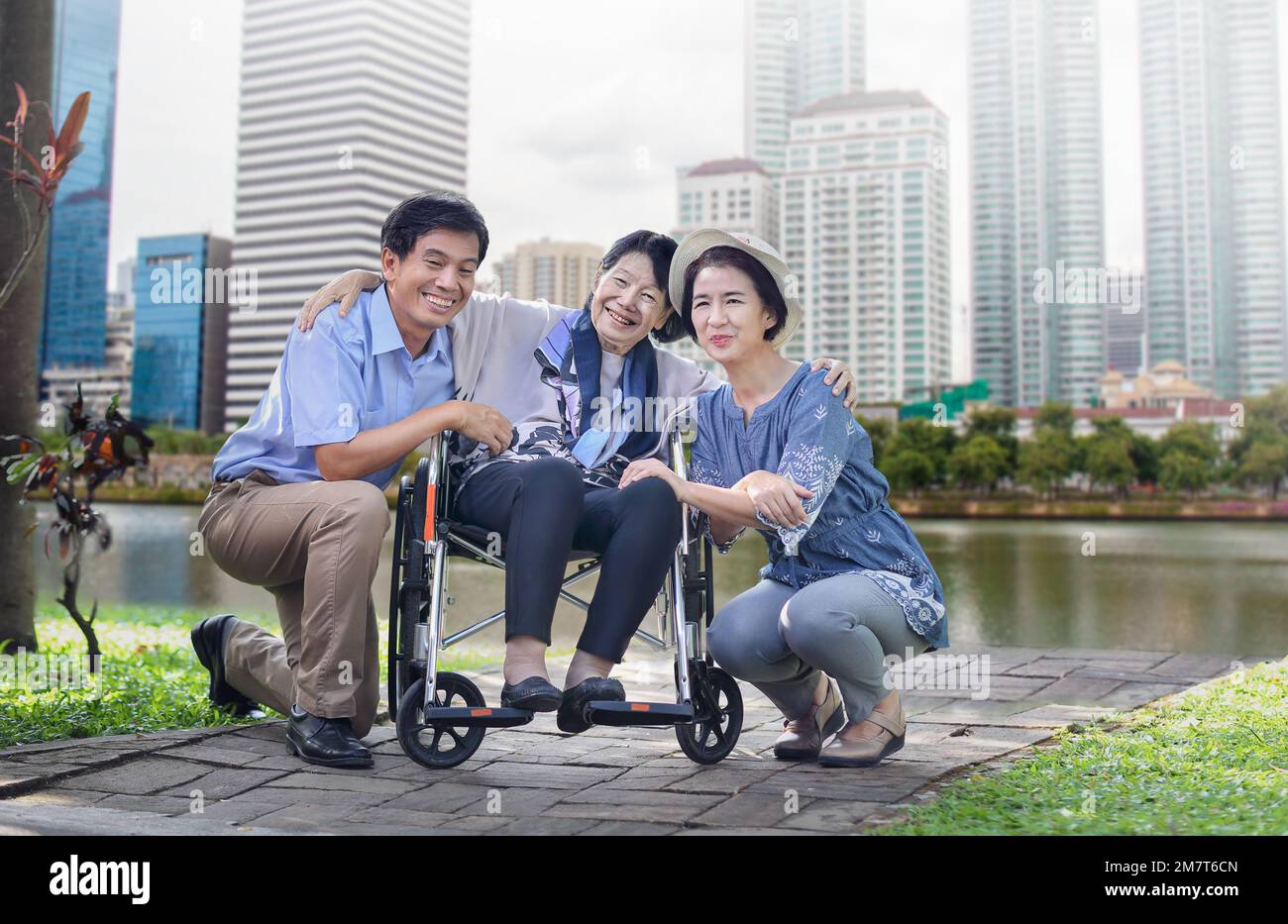 Son and daughter in law looking after elderly mother in backyard Stock Photo