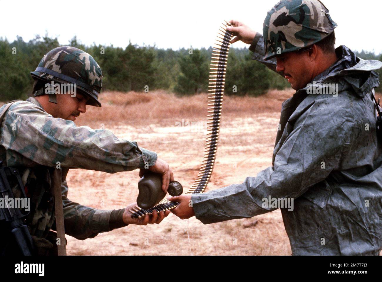 Sergeant John Ross and AIRMAN 1ST Class Charles Harger clean sand off a belt of M60 machine gun ammunition during exercise BOLD EAGLE '82. Subject Operation/Series: BOLD EAGLE '82 Base: Eglin Air Force Base State: Florida (FL) Country: United States Of America (USA) Stock Photo