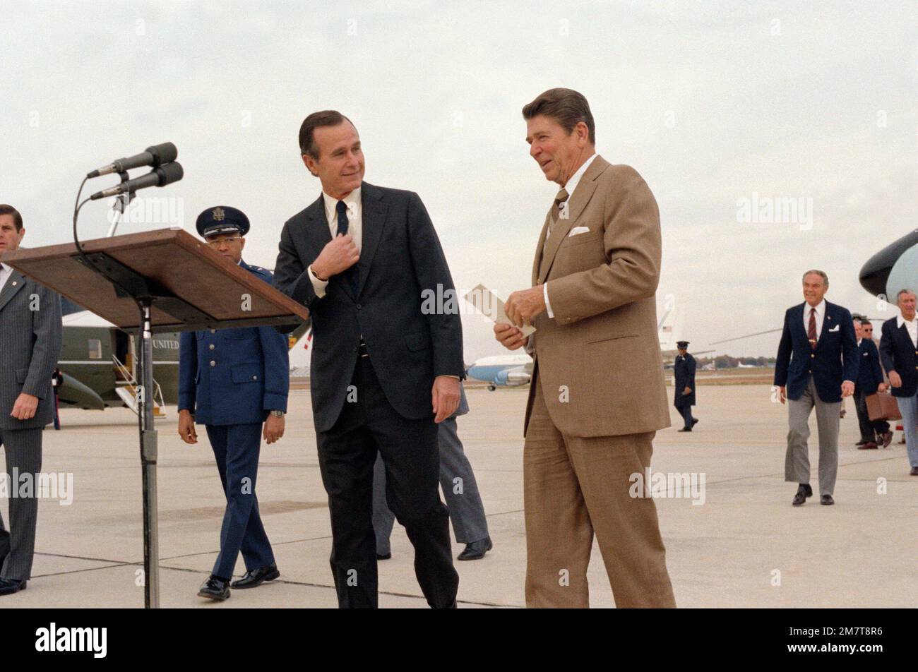 President Ronald Reagan approaches a speakers podium to welcome arriving foreign dignitaries, along with Vice President George Bush, at left. Base: Andrews Air Force Base State: Maryland (MD) Country: United States Of America (USA) Stock Photo