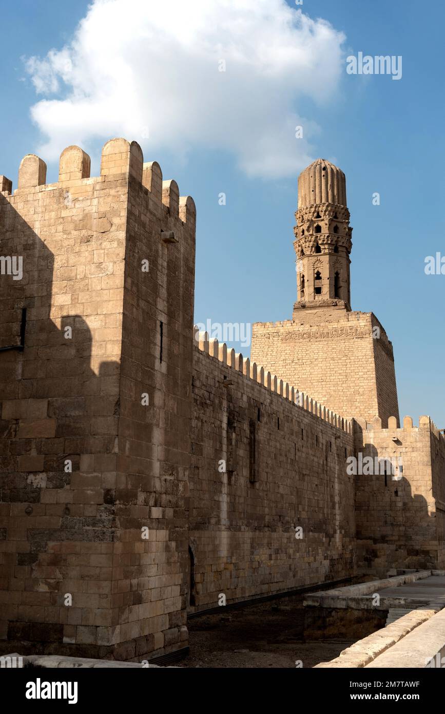 Cairo, Egypt, November 26th 2022 Minaret of the Al Hakim Mosque with the fortified defensive Northern walls of Islamic Cairo, near Bab El Futuh one of Stock Photo