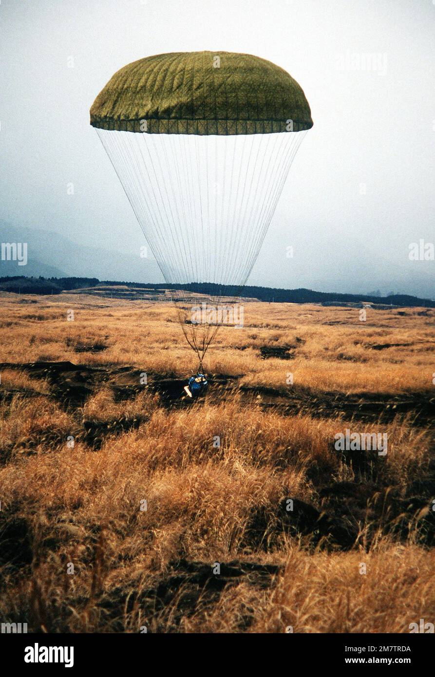 A pallet containing two 55-gallon drums of water, lands at the Fuji Drop Zone by parachute. The pallet was dropped from a C-130 Hercules aircraft. Base: Marine Corps Base, Camp Fuji State: Honshu Country: Japan (JPN) Stock Photo