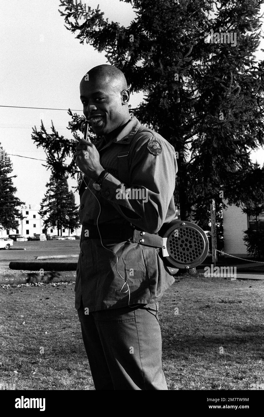 A soldier demonstrates a mobile public address system, complete with back pack speakers and a