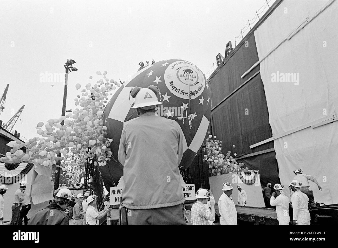 Shipyard workers watch the nuclear-powered attack submarine USS BUFFALO ...