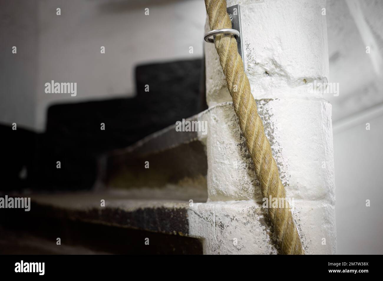 Spiral staircase with a rope climbing to the top, metal ring, white ...