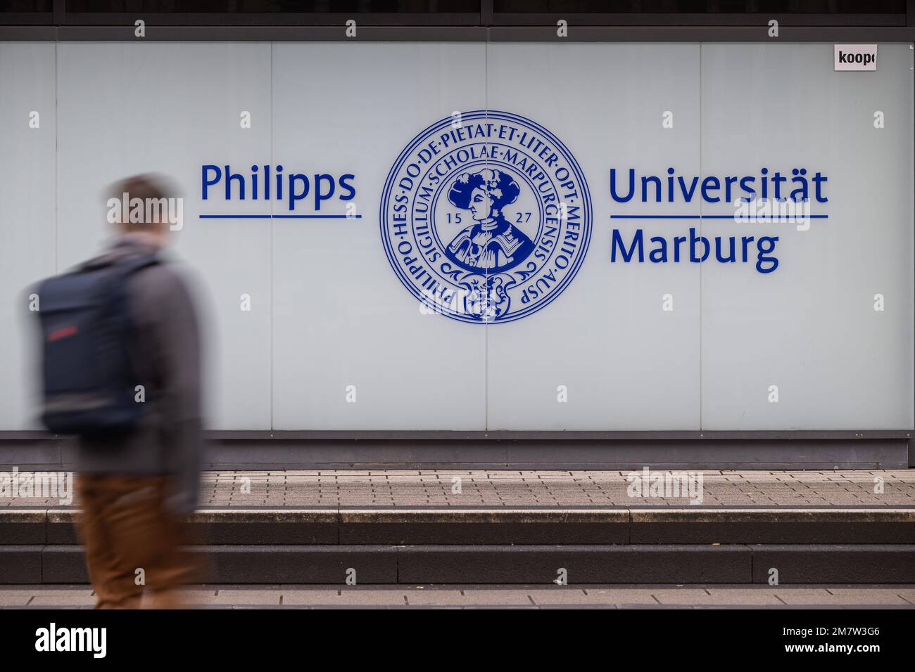 Marburg, Germany. 10th Jan, 2023. A man passes in front of the logo of