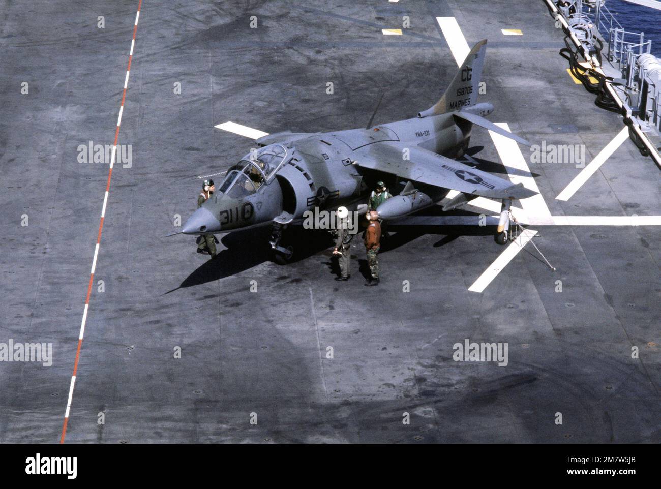 Flight deck crewmen prepare an AV-8A Harrier aircraft for flight aboard ...