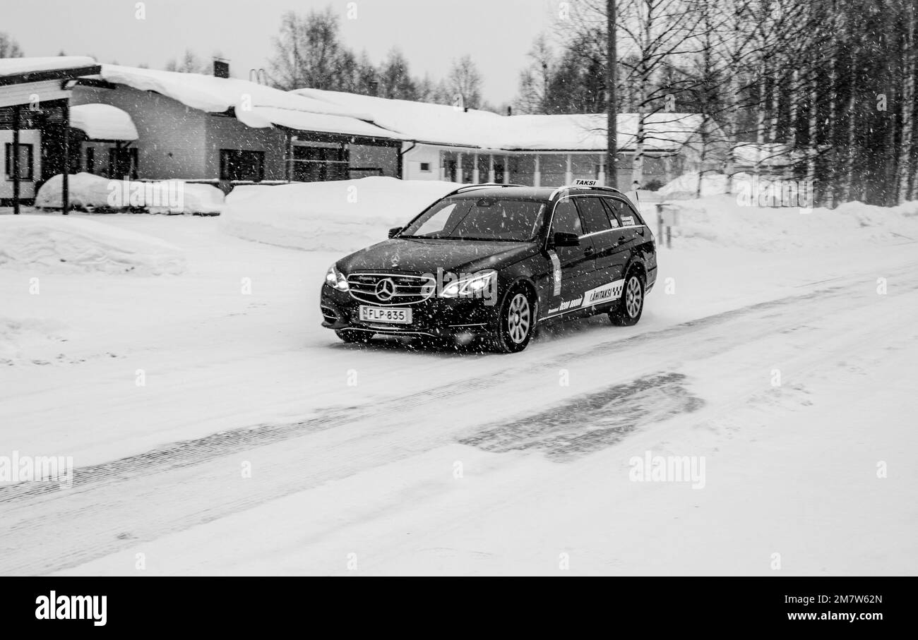 A black Mercedes-Benz car parked in the street in front of the houses ...