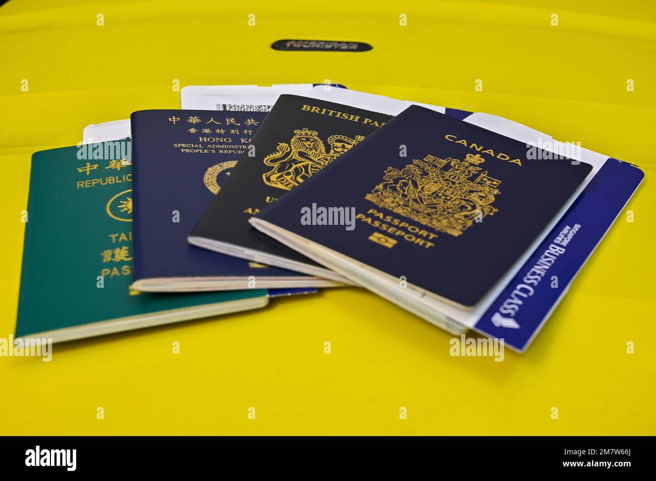 Passports with Business Class ticket, yellow luggage as background Stock Photo