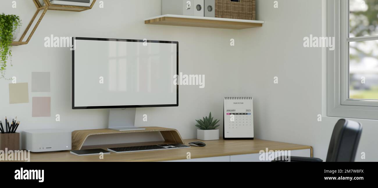 Minimalist white working space interior design with PC desktop computer mockup, keyboard, calendar, stationery and decor on wood table against the whi Stock Photo