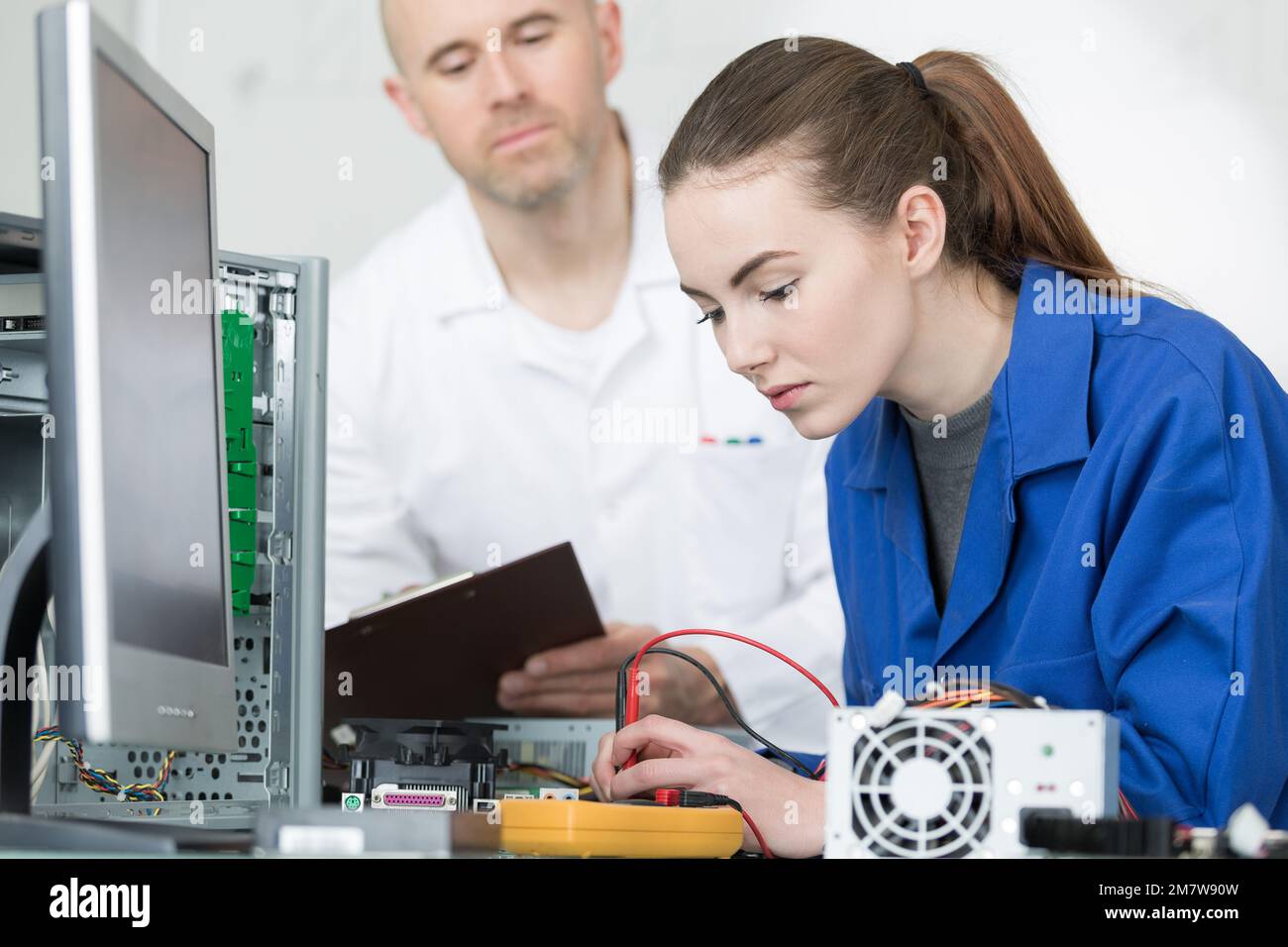 Young woman using multimeter on computer components Stock Photo