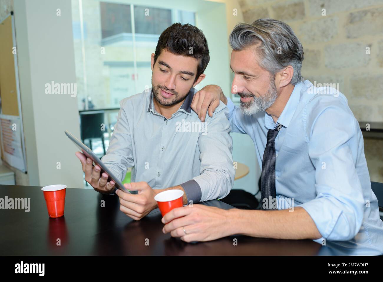 friendly businessmen looking at tablet while on break Stock Photo