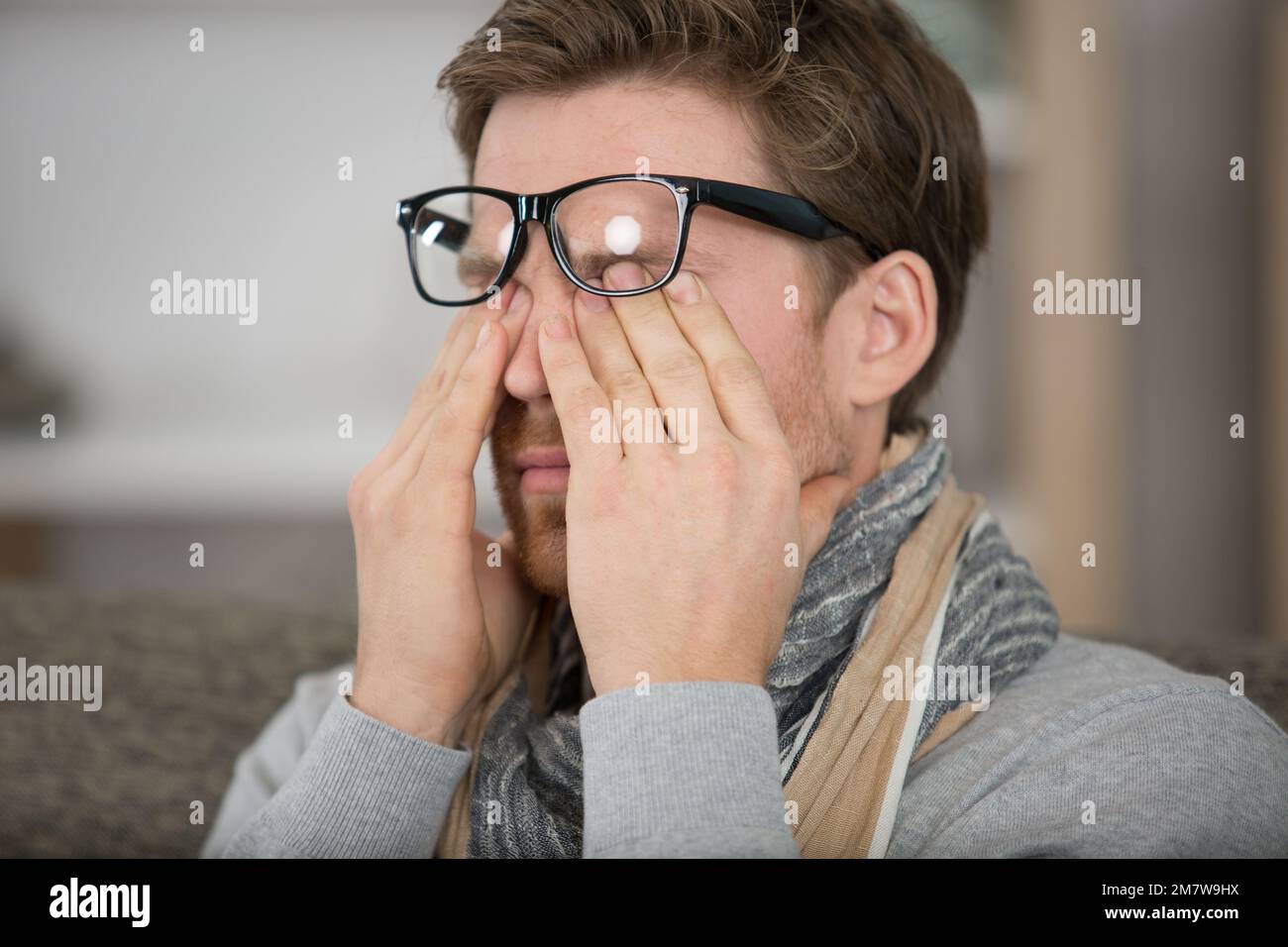 a man rubbing eye at home annoying itch Stock Photo