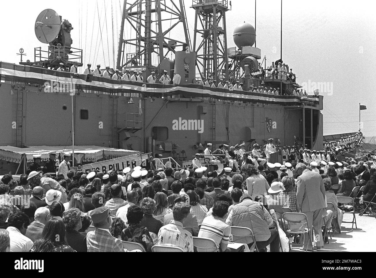 A view of the crowd attending the commissioning ceremony for the guided missile frigate USS LEWIS B. PULLER (FFG-23). In the background the crew mans the rails of the frigate. Base: Naval Air Station, Long Beach State: California (CA) Country: United States Of America (USA) Stock Photo