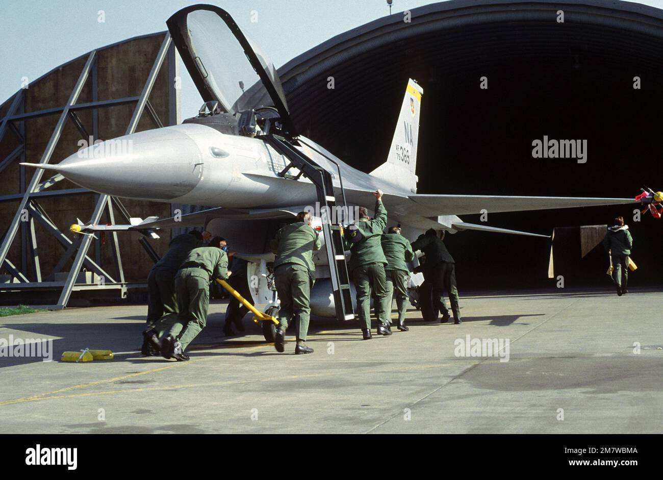 Ground crewmen manually push an F15 Fighting Falcon aircraft from the