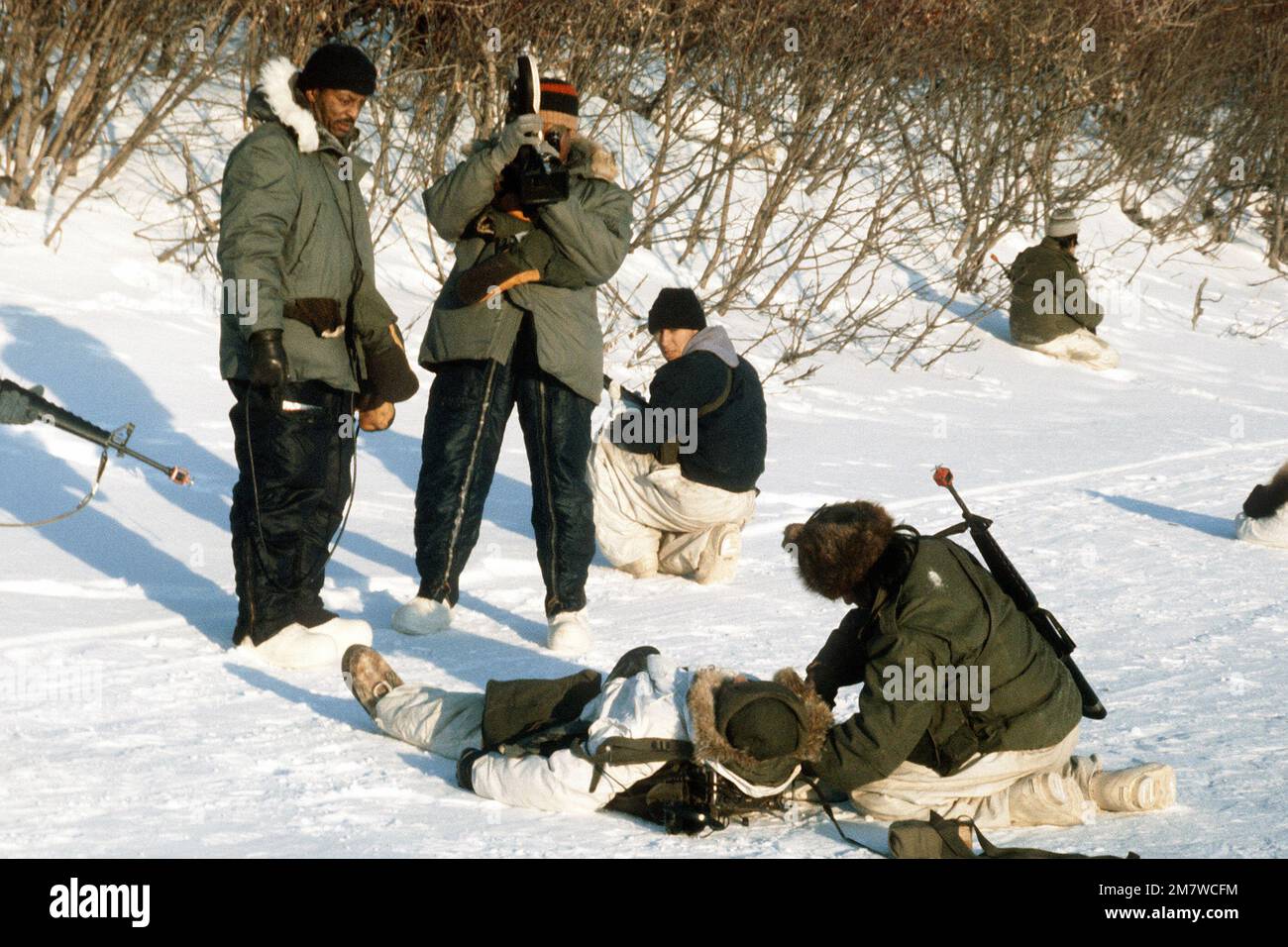 A motion picture specialist shoots 16mm film footage of a 'wounded' soldier during Exercise Cool Snowhog '82. Subject Operation/Series: COOL SNOWHOG '82 Base: Kotzebue State: Alaska (AK) Country: United States Of America (USA) Stock Photo