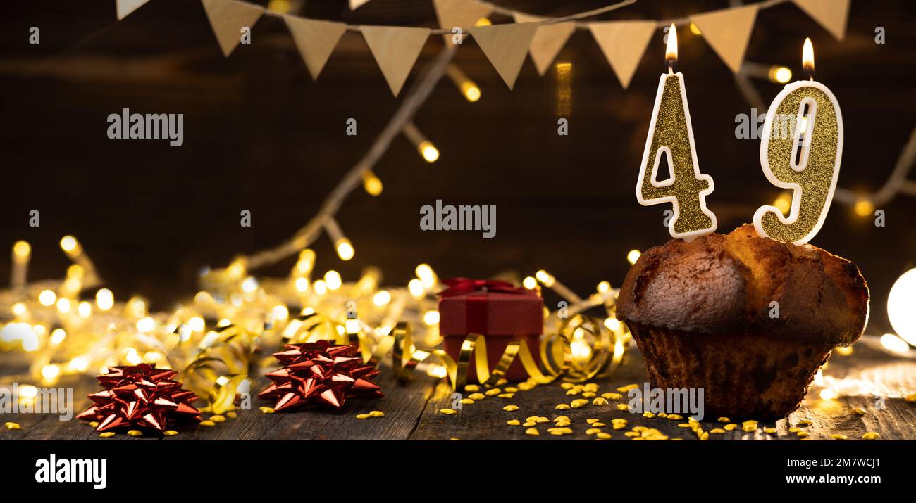 Number 49 golden festive burning candles in a cake, wooden holiday background. forty-nine years from the date of birth. the concept of celebrating a b Stock Photo