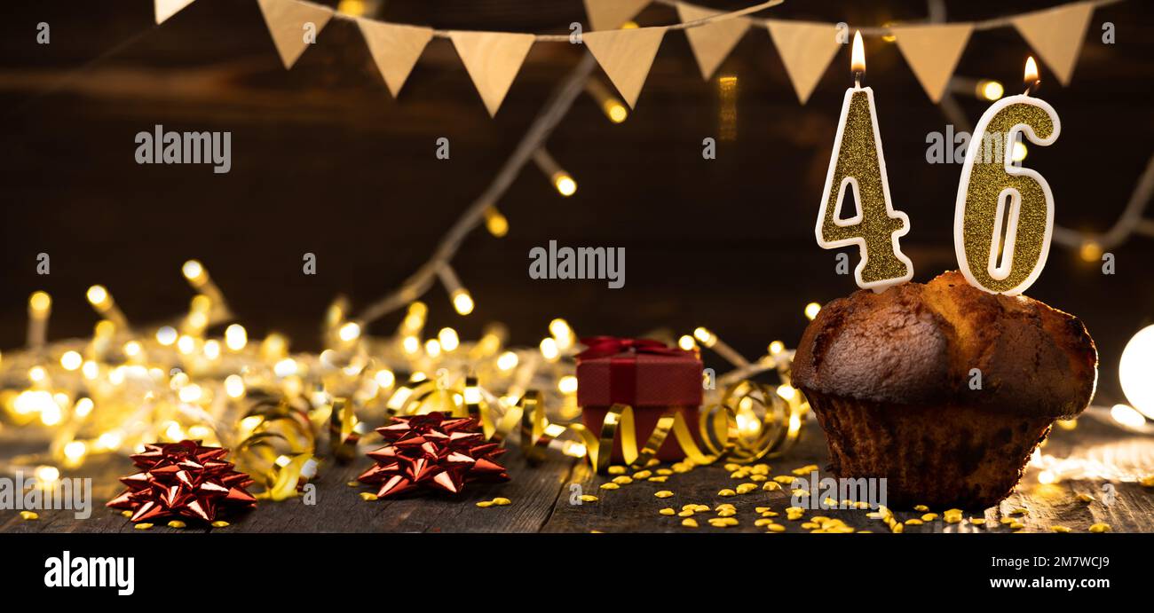 Number 46 golden festive burning candles in a cake, wooden holiday background. forty-six years from the date of birth. the concept of celebrating a bi Stock Photo