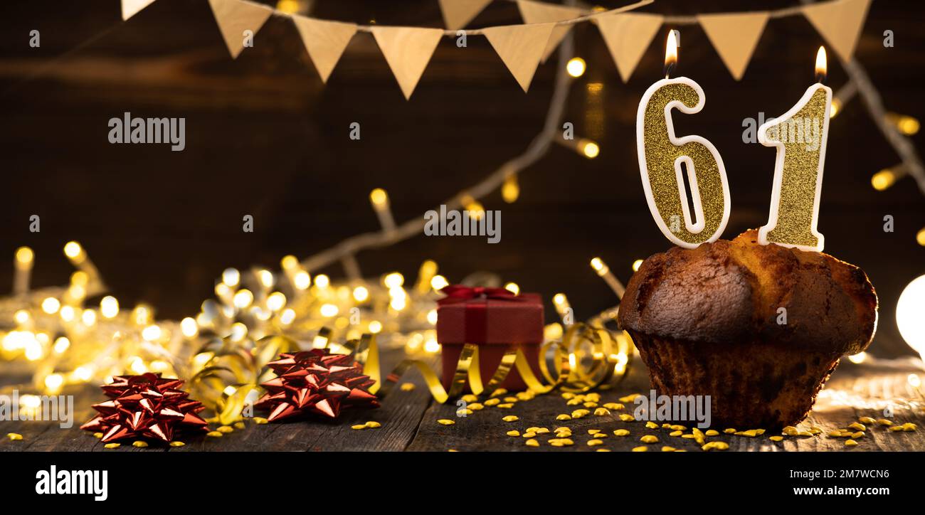 Number 61 golden festive burning candles in a cake, wooden holiday background. sixty-one years since the birth. the concept of celebrating a birthday, Stock Photo