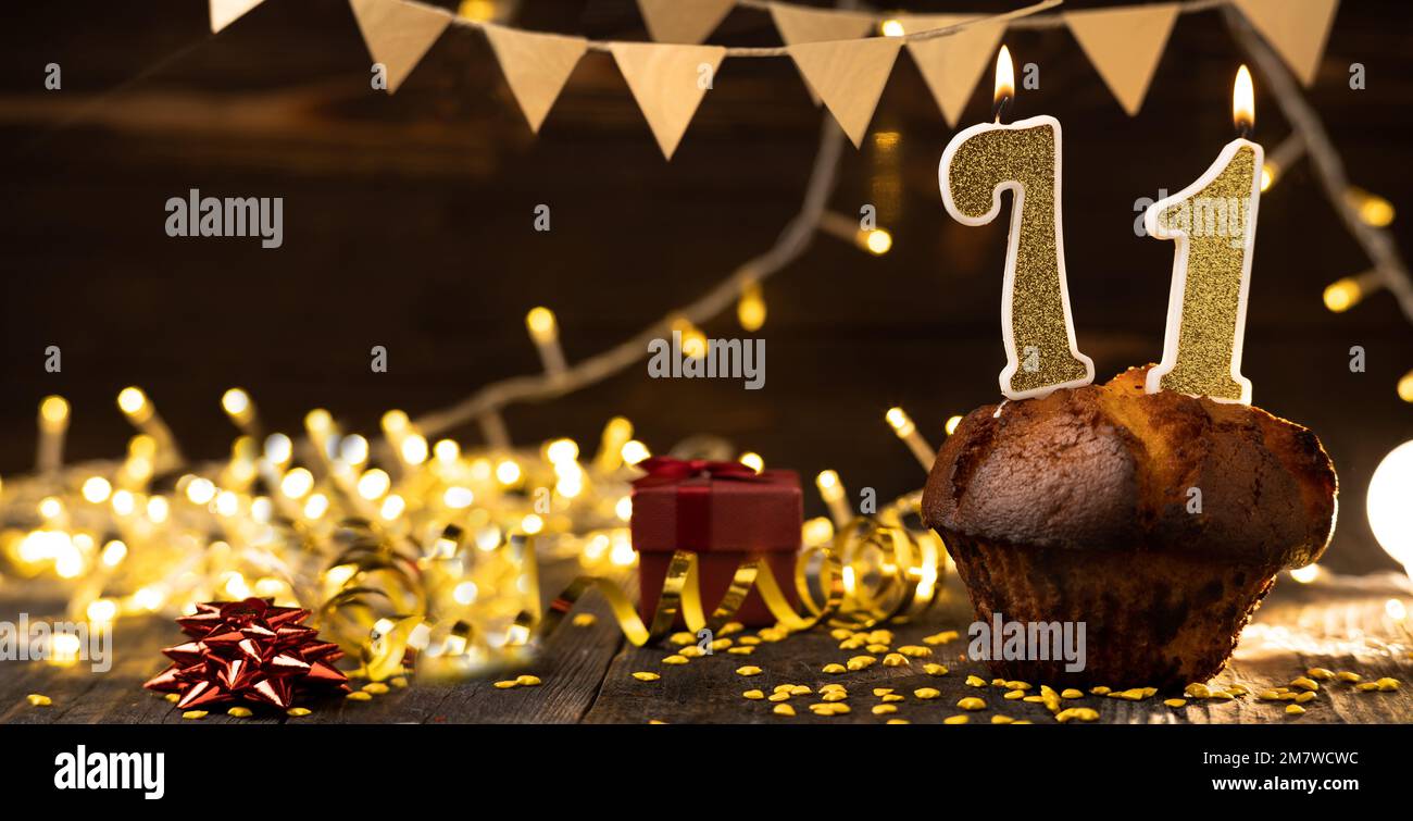 Number 71 golden festive burning candles in cake, wooden holiday background. seventy-one years since the birth. the concept of celebrating a birthday, Stock Photo