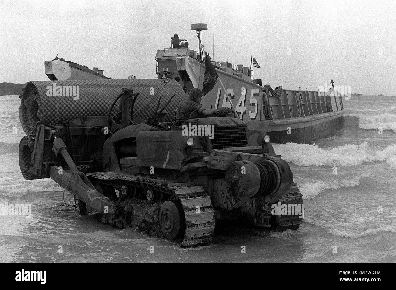 A U.S. Marine uses a bulldozer to unload materials, used to create a beach landing zone, from the utility landing craft (LCU-1645) during Operation Ocean Venture '82. Subject Operation/Series: OCEAN VENTURE '82 Base: Vieques Country: Puerto Rico (PRI) Stock Photo