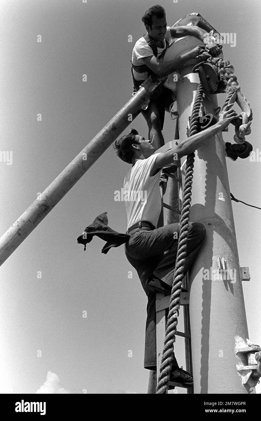 Boatswain's Mate SEAMAN (BMSN) John Vieira (on ladder) hooks a cable to