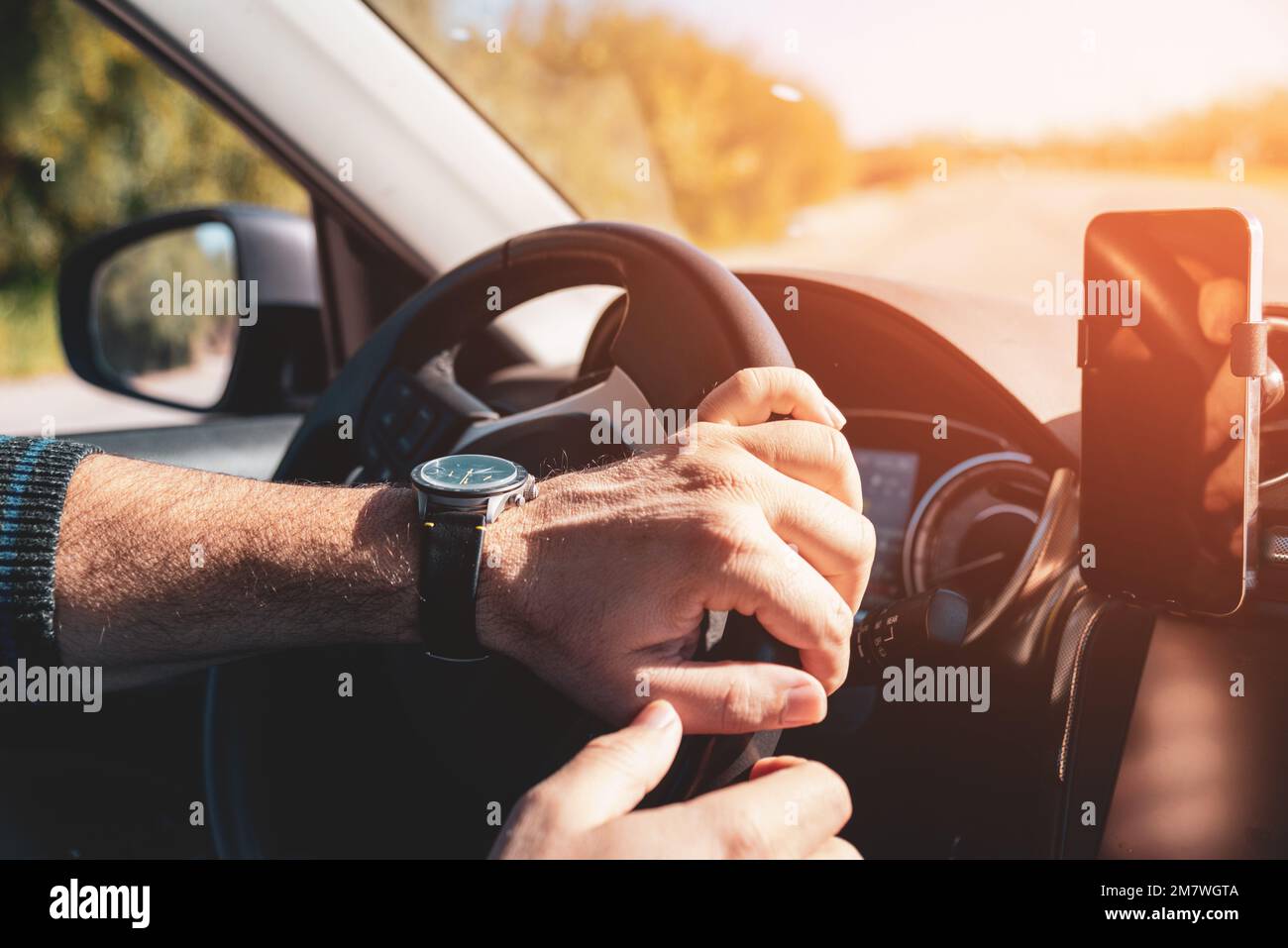 Man with both hands on steering wheel driving at sunset Stock Photo Alamy