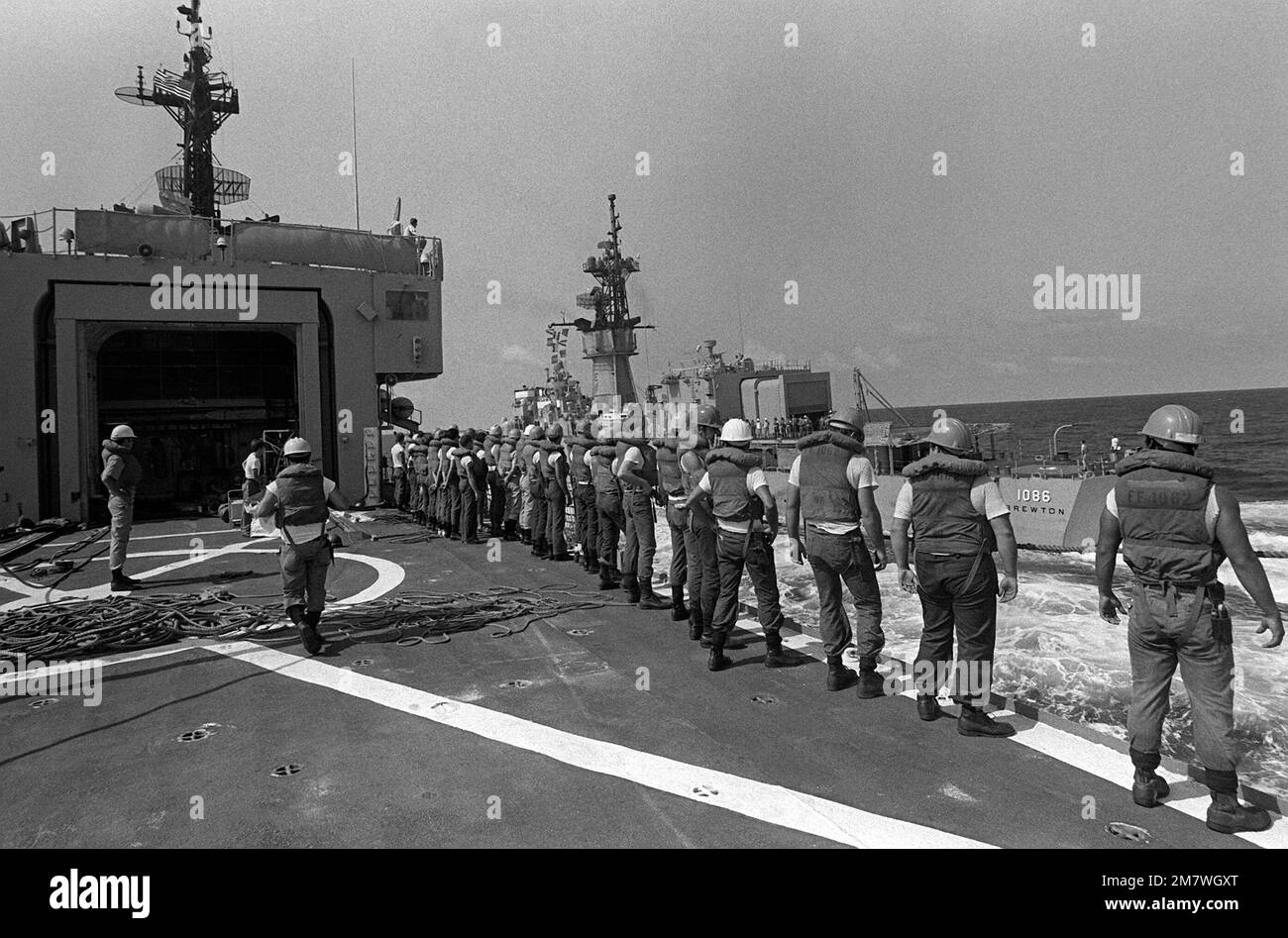 Crew members aboard the frigate USS WHIPPLE (FF1062) stand at the ship